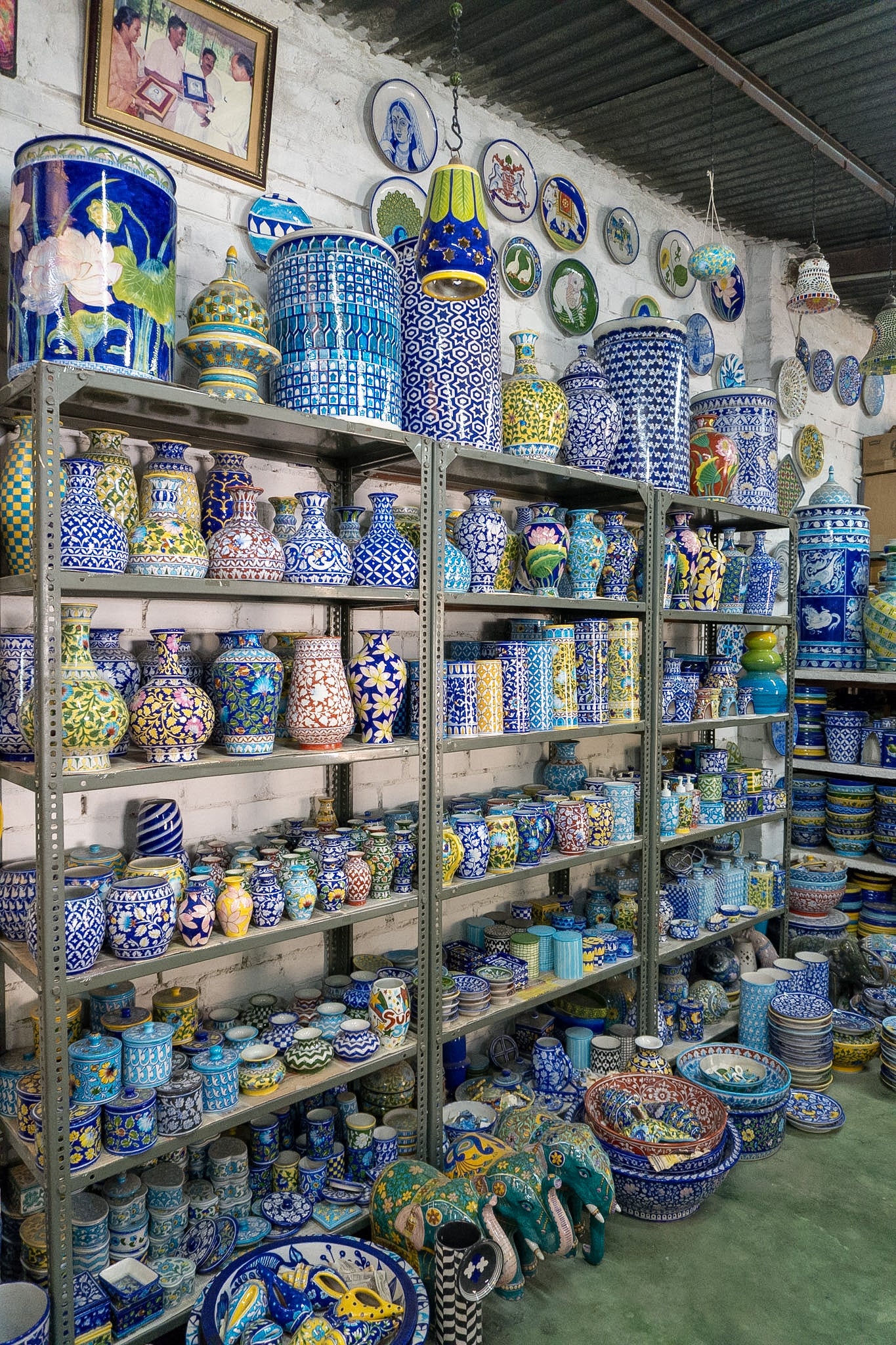 Shelves filled with various colorful ceramic pots and vases in a store.
