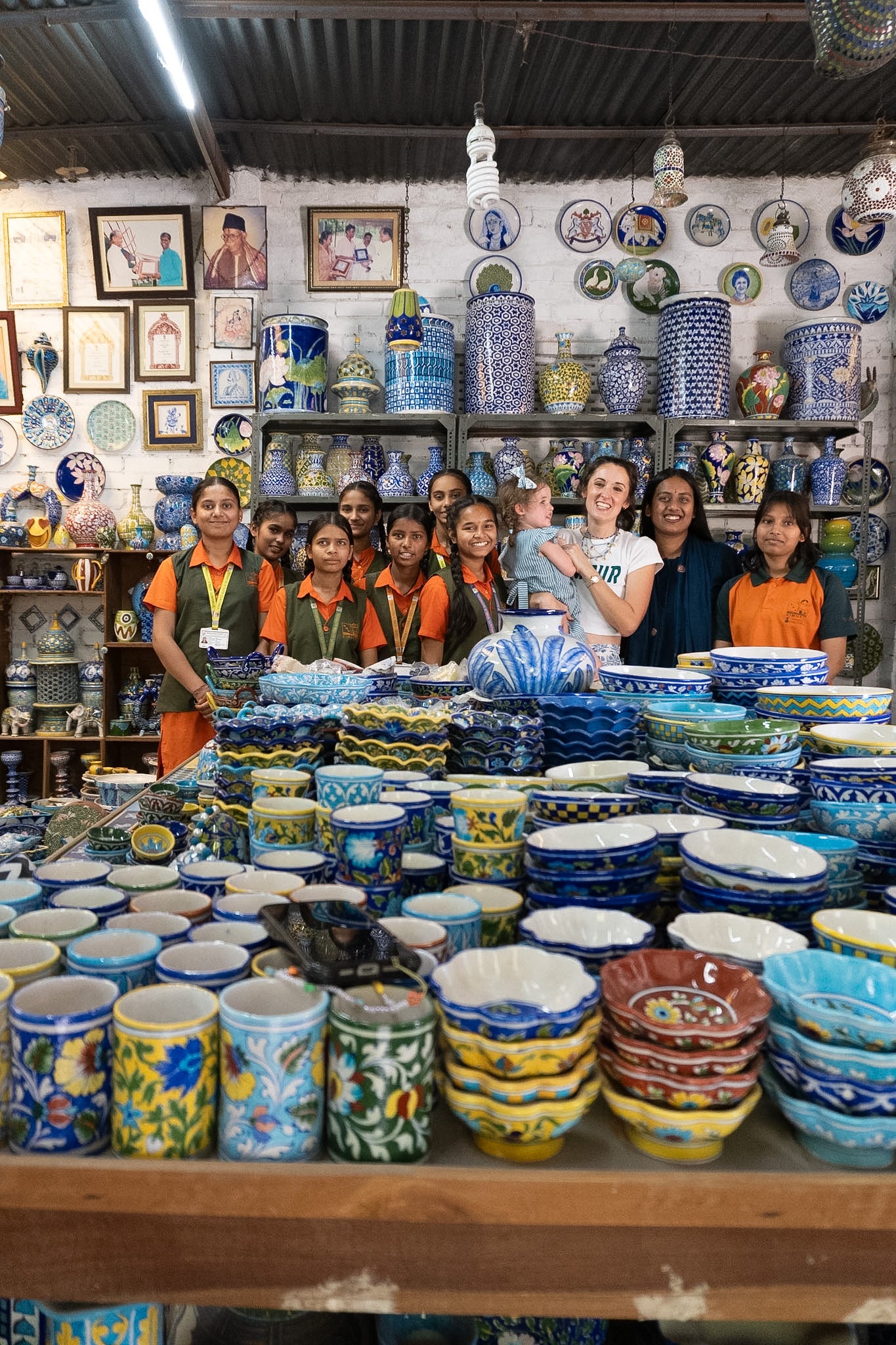 Group of people in a pottery store with shelves of ceramic items.