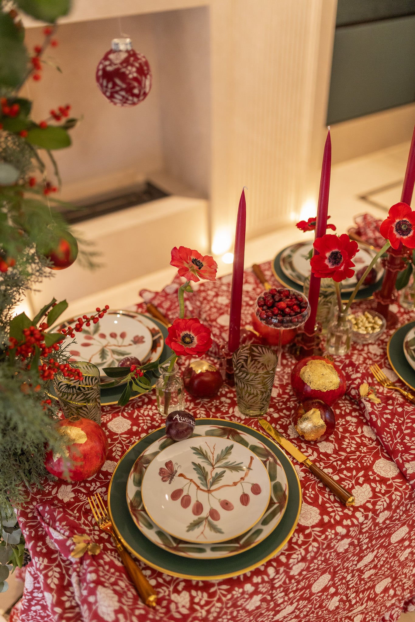 Decorative Christmas table setting with red tablecloth, candles, and festive decorations.