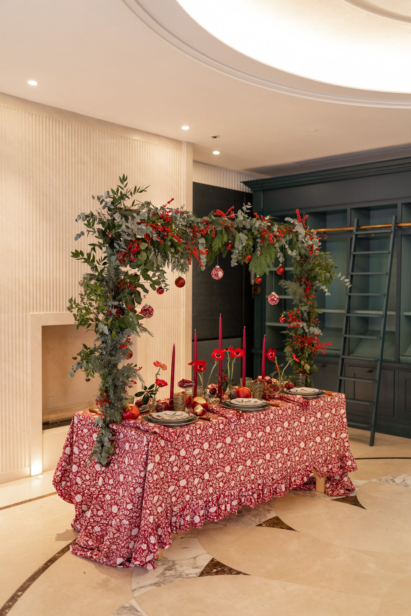 Decorative table setting with floral arrangements and red candles in a formal room.