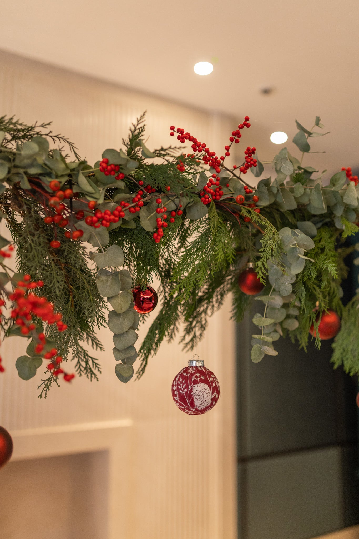 Decorative Christmas garland with red berries and ornaments on a neutral background