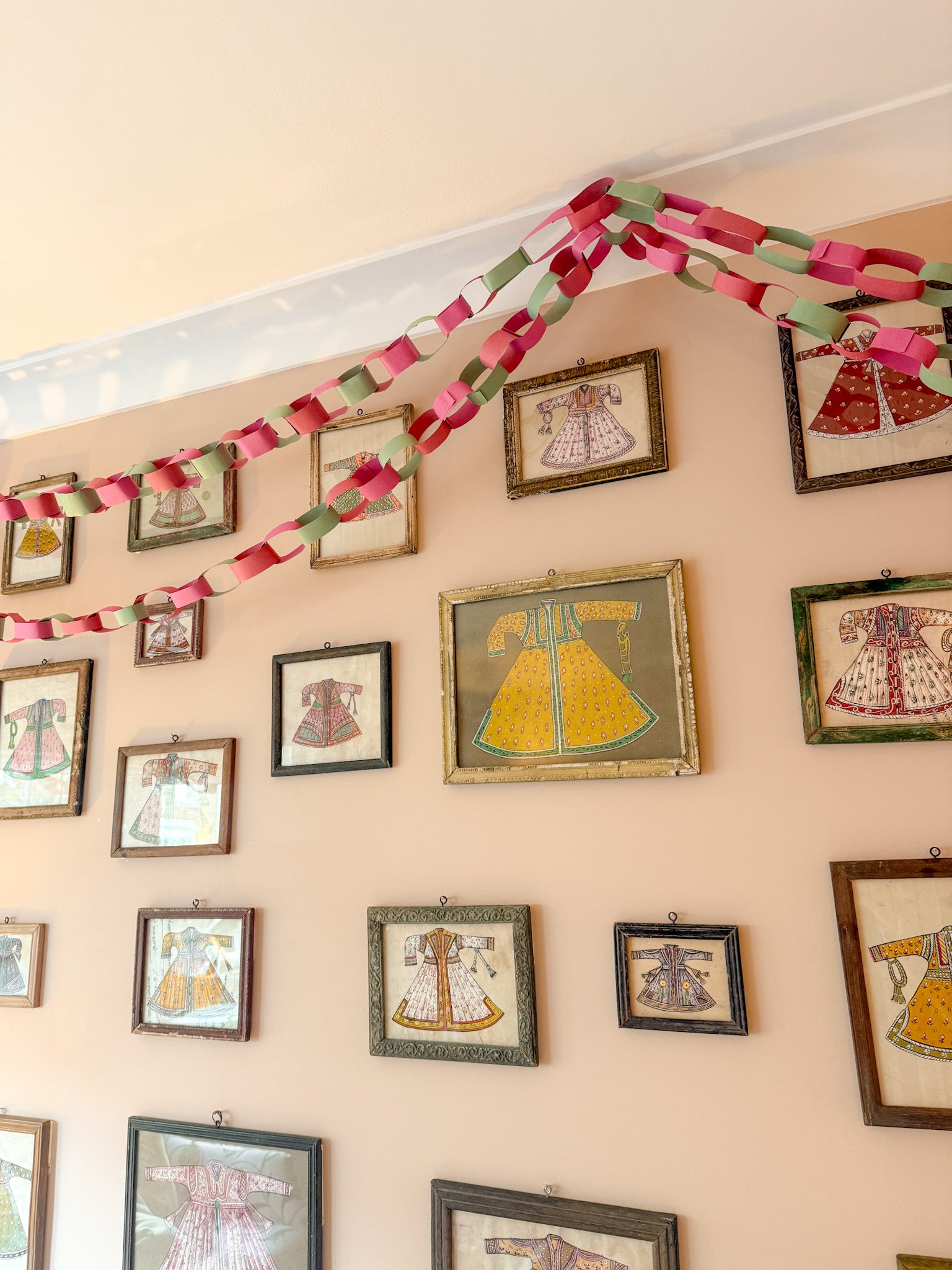 Wall with framed dresses and a colourful paper chain