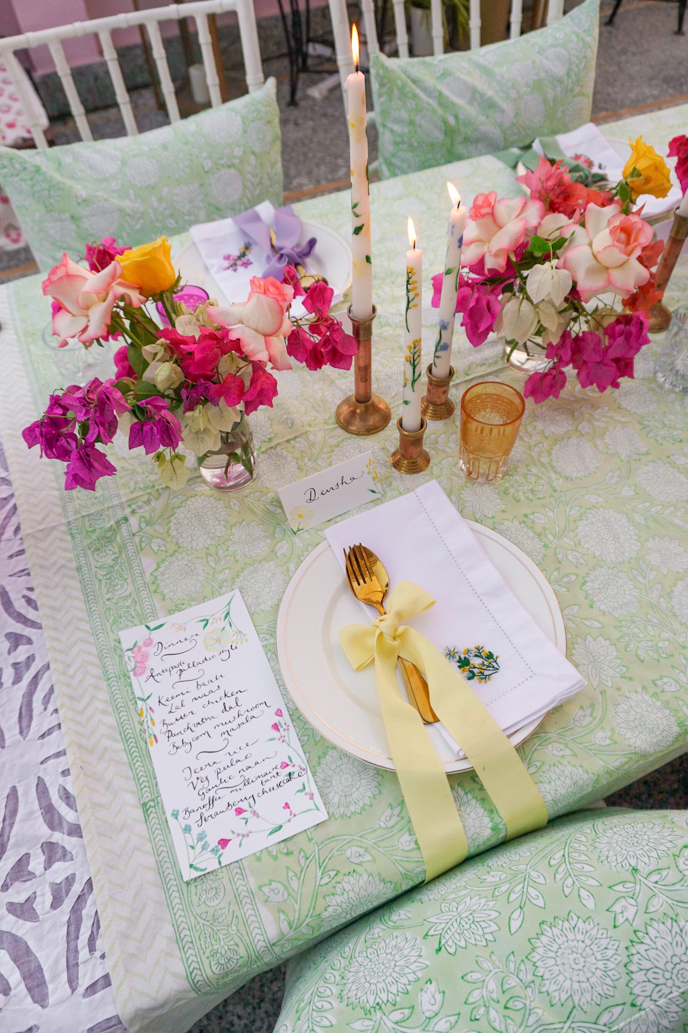 Details on a rainbow tablescape by Rosanna Falconer with floral embroidered napkin and block printed green tablecloth as well as a calligraphy menu