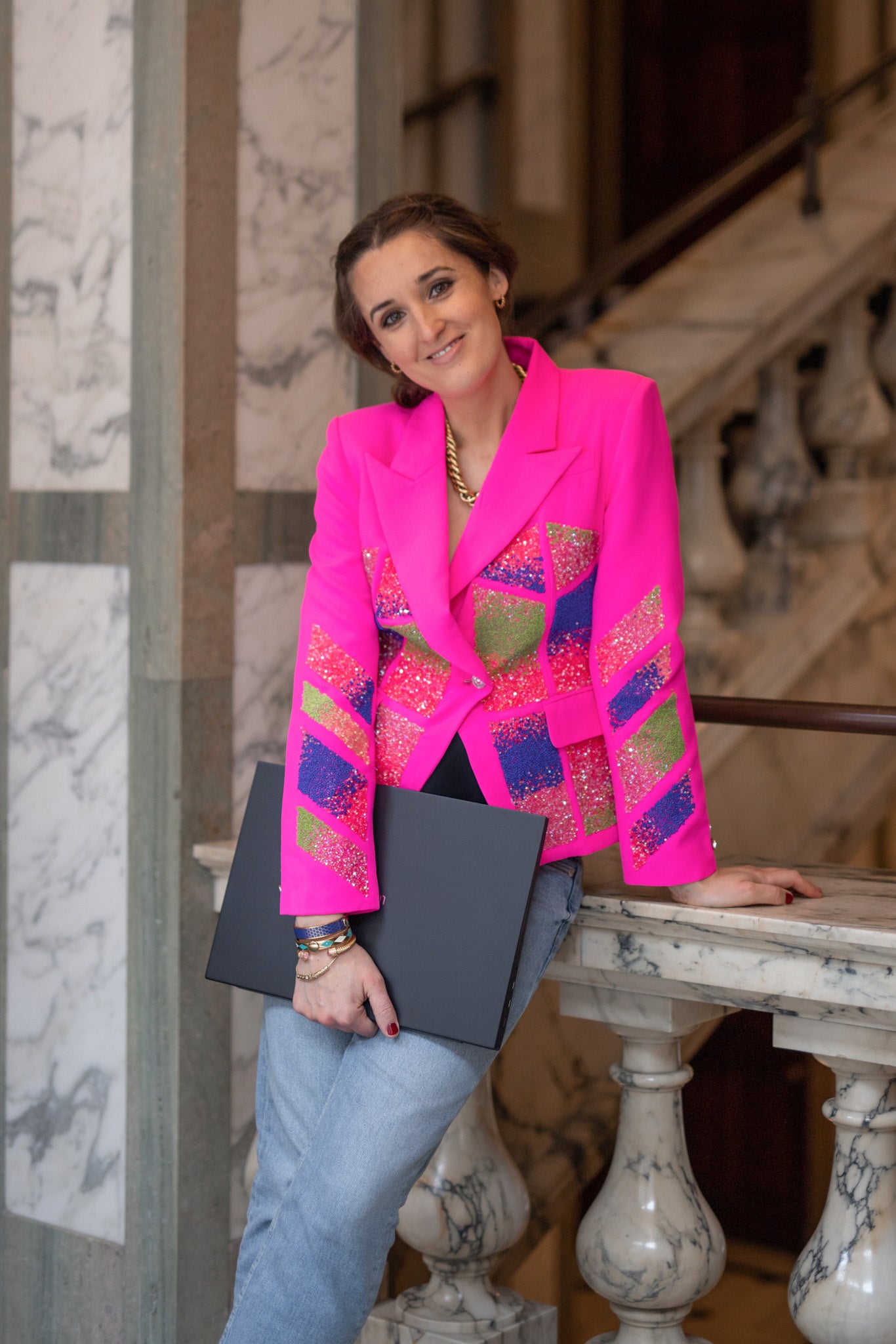 Rosanna Falconer in pink blazer holding laptop