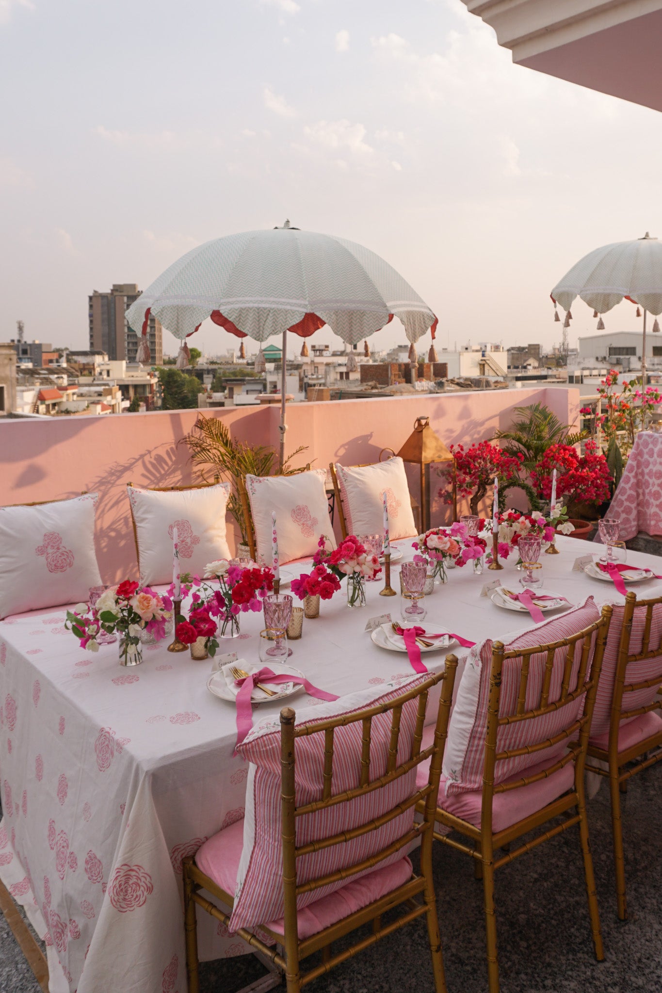 Rosanna Falconer pink tablescape in Jaipur with long table, chairs, cushions and parasols
