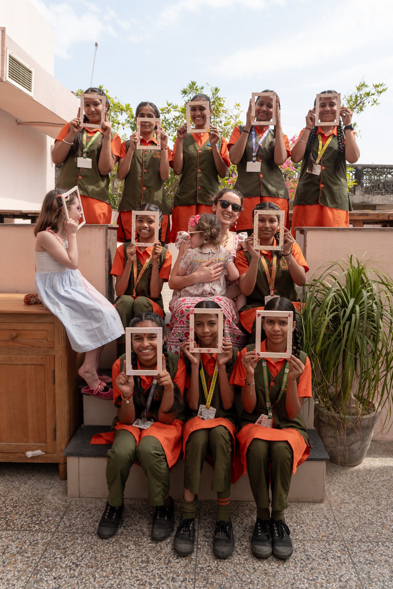 Group of people in uniform holding framed pictures, with a woman and child in front.